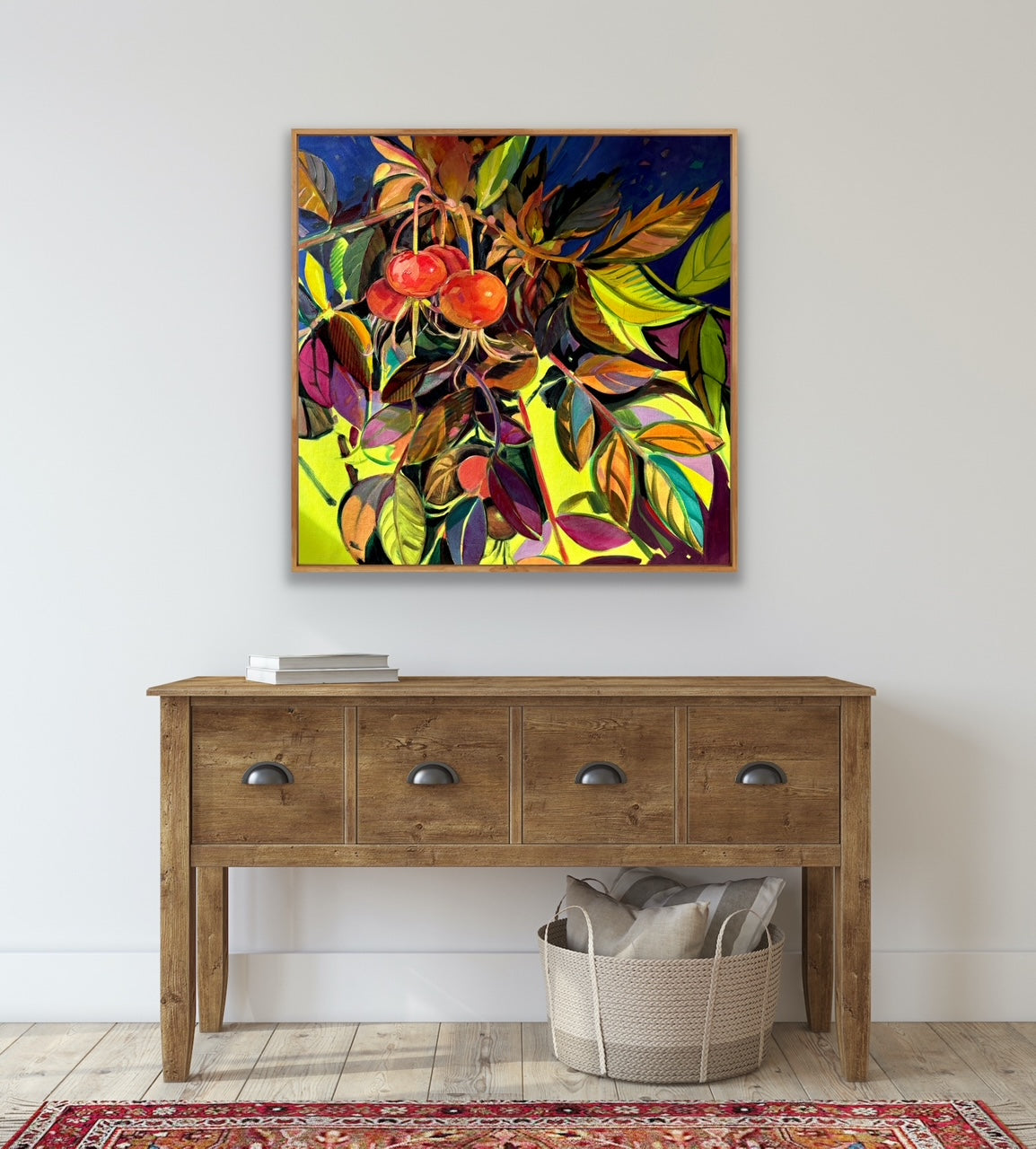 Colorful abstract painting above a wooden console table with a basket and pillows on a light gray background.